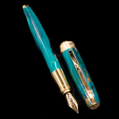 A full view of the Visconti Van Gogh Fountain Pen - The Novel Reader uncapped, with its cap laying next to the pen. 