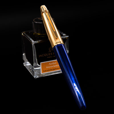 Waterman Edson Sapphire Fountain Pen - Preowned capped, leaning against an ink bottle. 