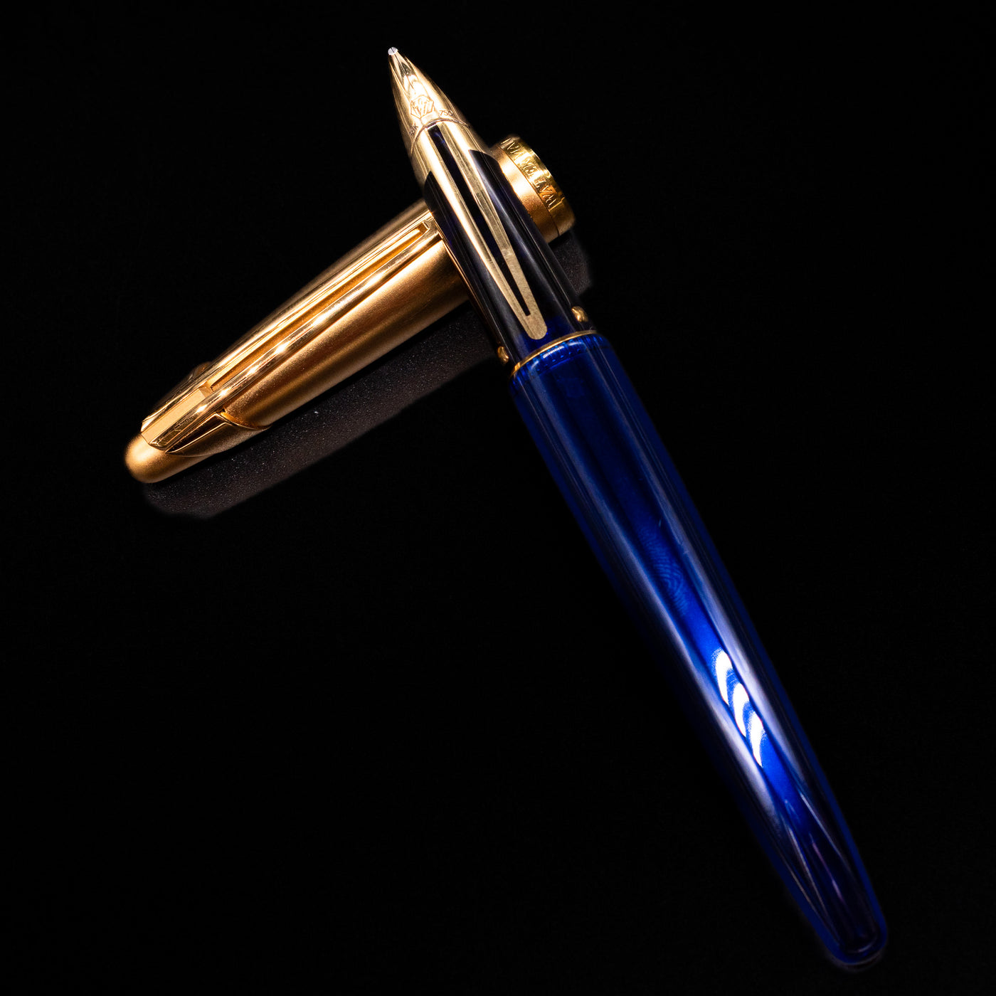 Waterman Edson Sapphire Fountain Pen - Preowned laying on top of its cap in a crossed position showing full view of the entire uncapped pen.