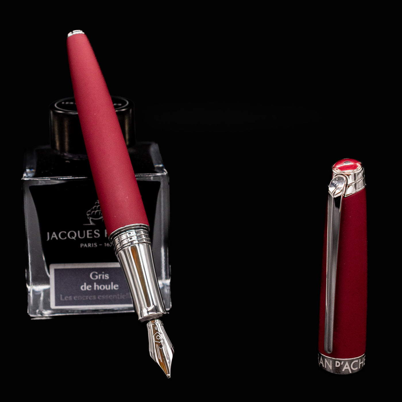 Uncapped Caran d’Ache Léman V2 Burgundy pen propped on ink bottle