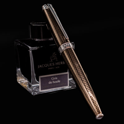 Caran d’Ache Léman V2 Caviar fountain pen, capped and leaning on an ink bottle