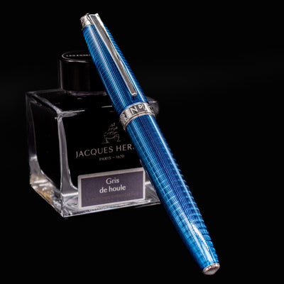 Caran d’Ache Léman V2 Grand Bleu, capped and propped on ink bottle