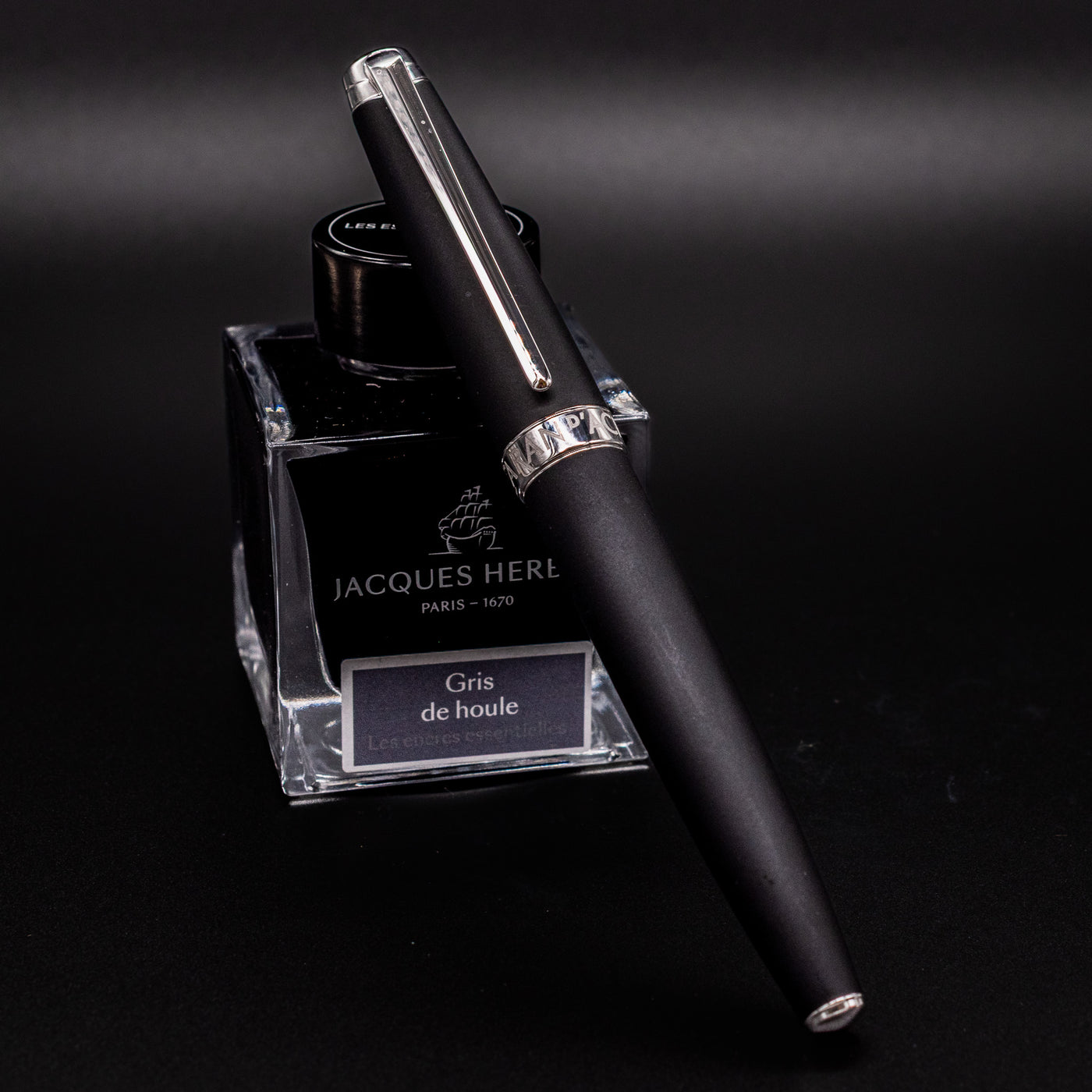Capped Caran d’Ache Léman V2 Matte Black fountain pen propped on ink bottle