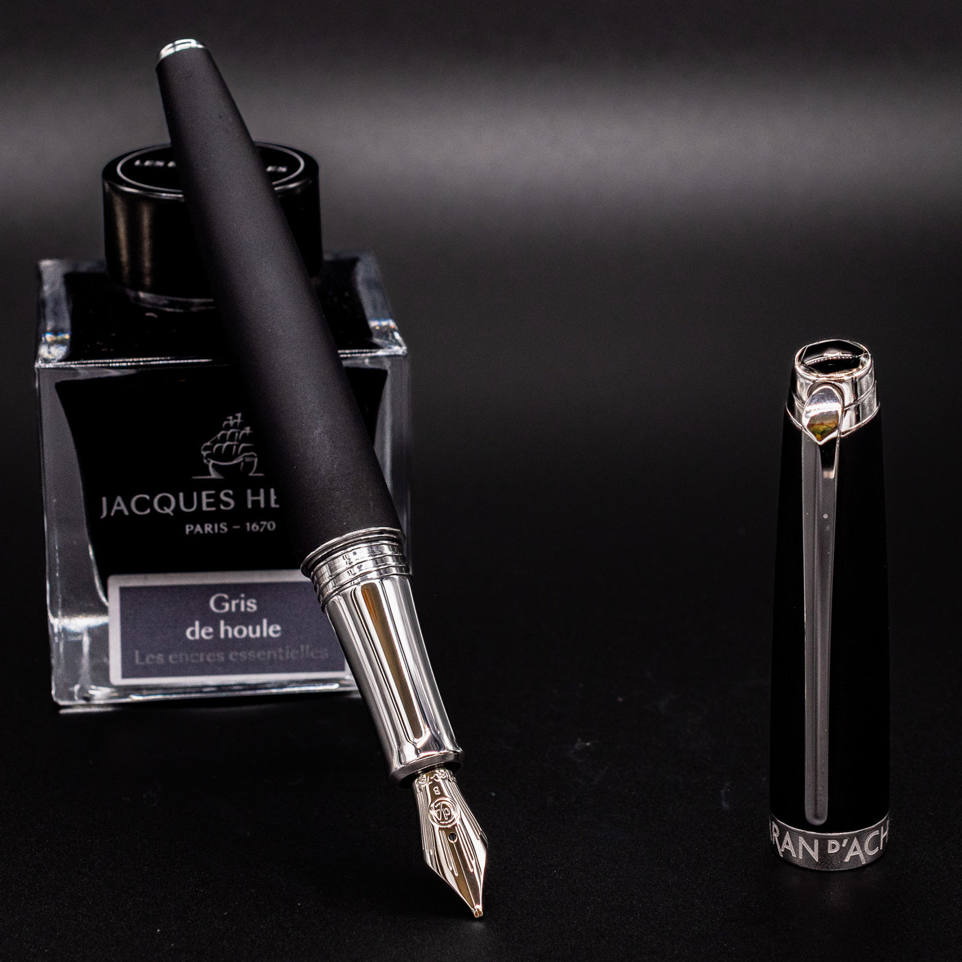 Uncapped Léman V2 Matte Black fountain pen resting on ink bottle