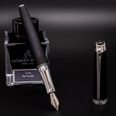 Uncapped Léman V2 Matte Black fountain pen resting on ink bottle