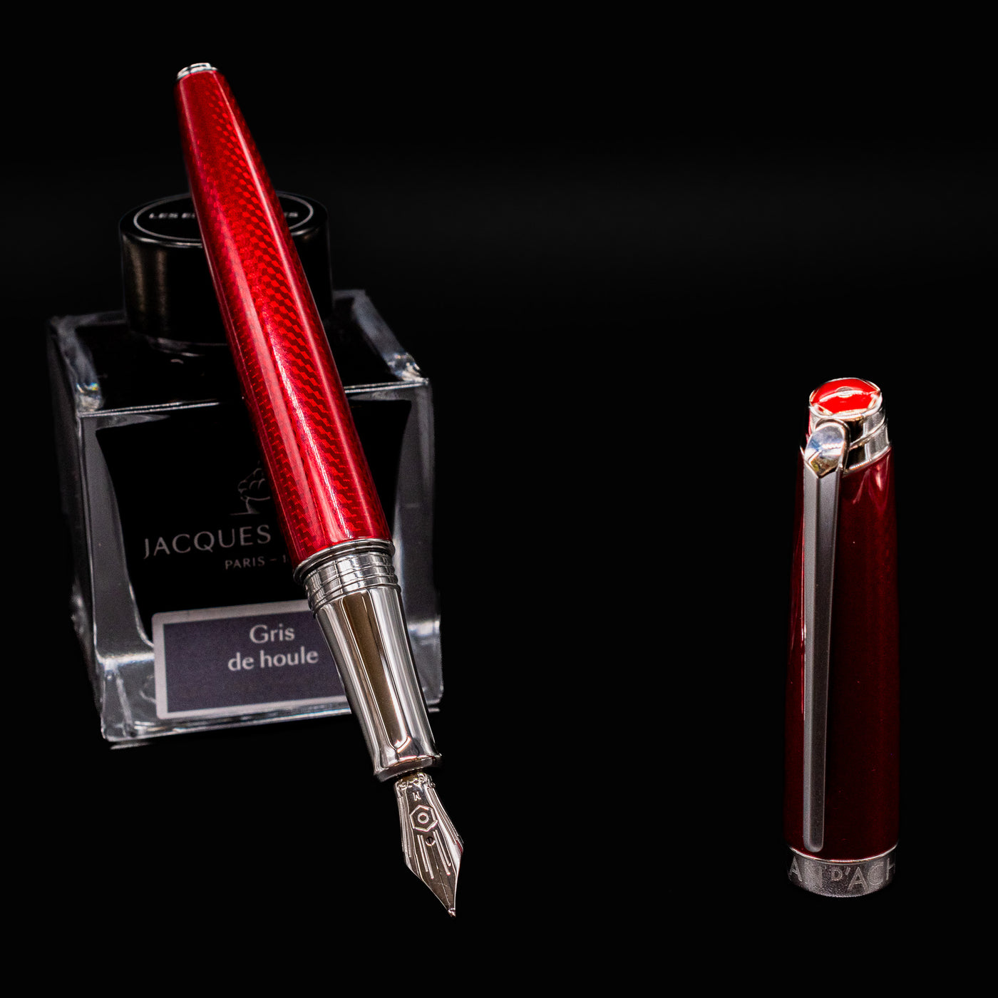 Uncapped Caran d’Ache Léman V2 Rouge Carmin pen leaning on ink bottle