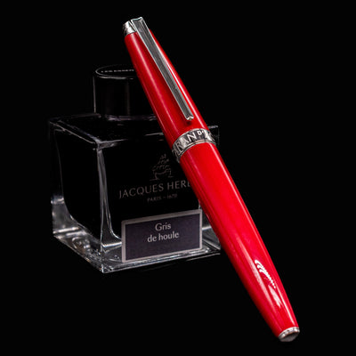 Léman V2 Scarlet fountain pen, capped and leaning on ink bottle