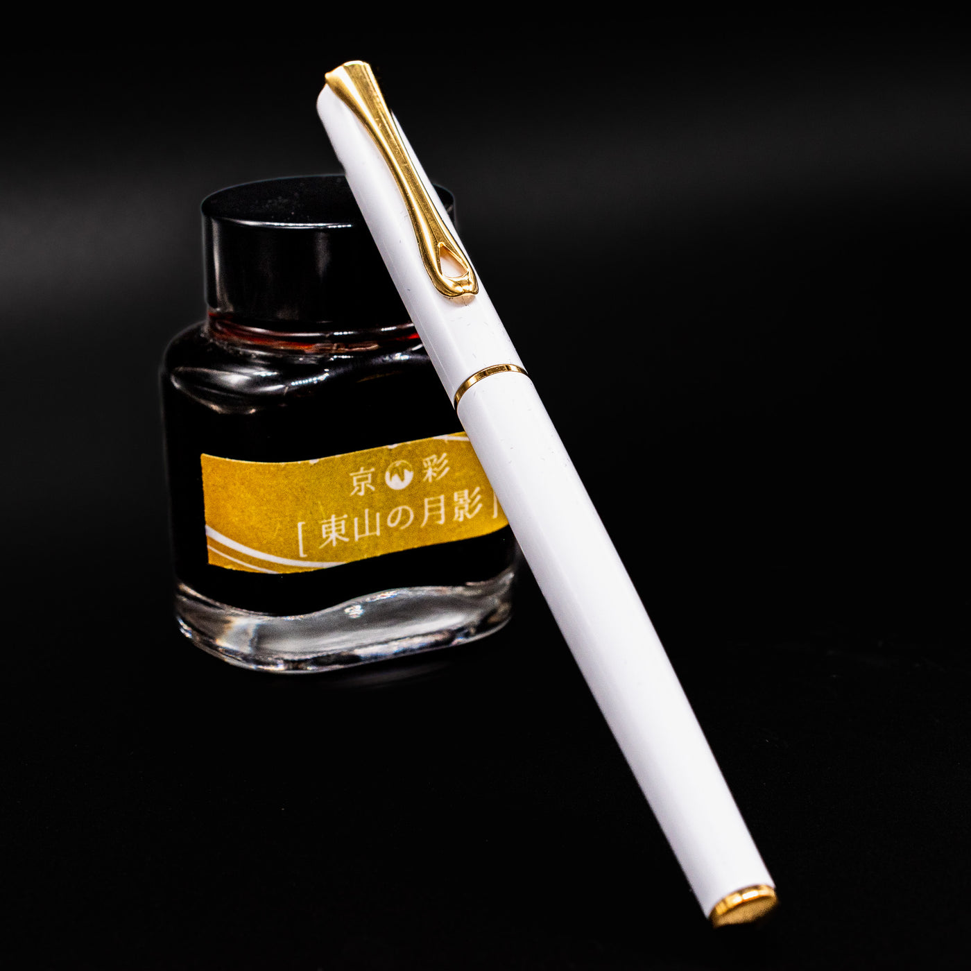Diplomat Traveller White & Gold Fountain Pen shown capped in front of an ink bottle