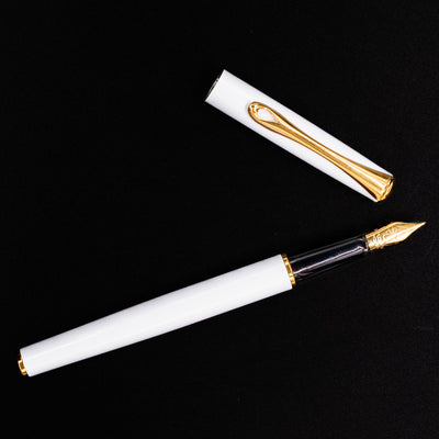 Full flat lay image of the Diplomat Traveller White & Gold Fountain Pen with cap beside it
