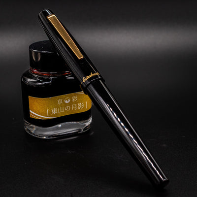 Esterbrook Camden Black & Gold fountain pen capped leaning on ink bottle - classy and modern design