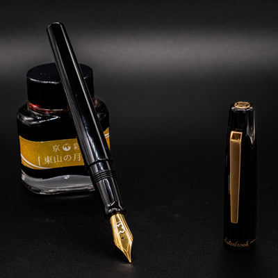 Esterbrook Camden Black & Gold fountain pen uncapped leaning on ink bottle - luxury modern fountain pen