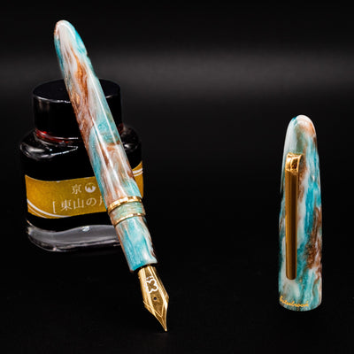 Esterbrook Estie Avalanche fountain pen uncapped leaning on ink bottle - luxury DiamondCast resin pen