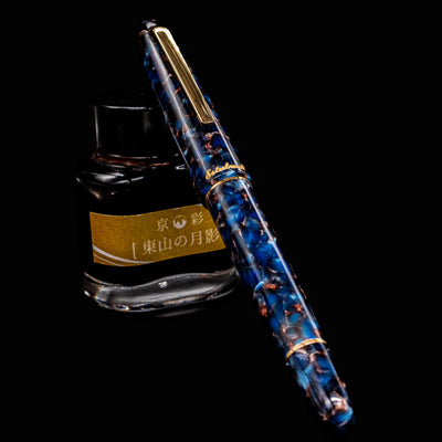 Esterbrook Estie Button Piston Fountain Pen in Nouveau Bleu resting on an ink bottle, full pen view with cap on