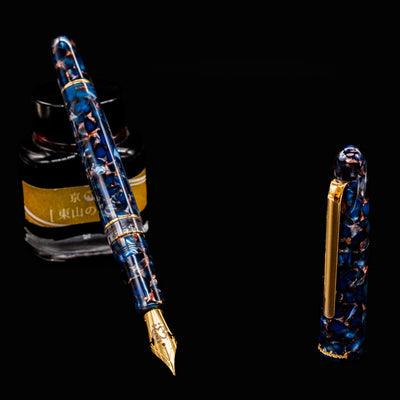 Esterbrook Estie Button Piston Fountain Pen in Nouveau Bleu with gold nib resting on ink bottle, cap off