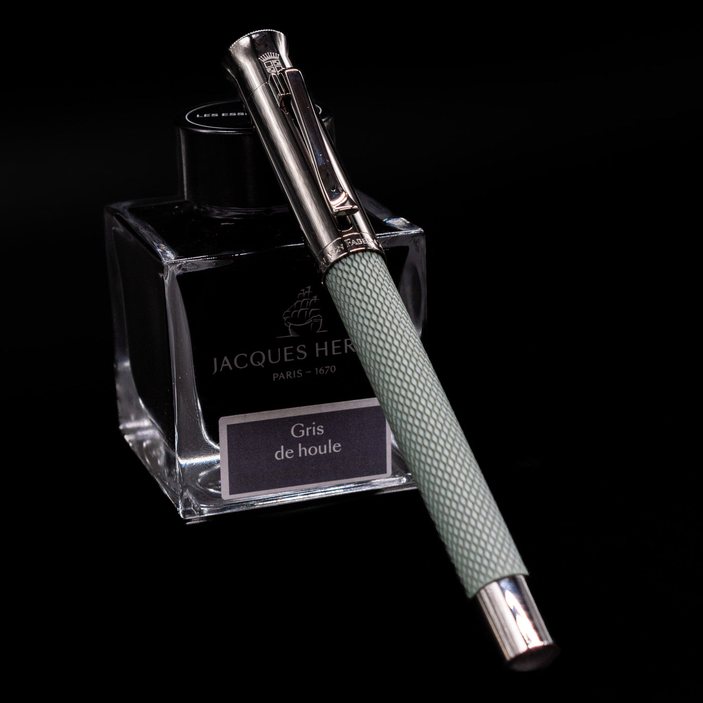 Graf von Faber-Castell Guilloche Fountain Pen in Sage Green, capped and resting on Jacques Herbin ink bottle