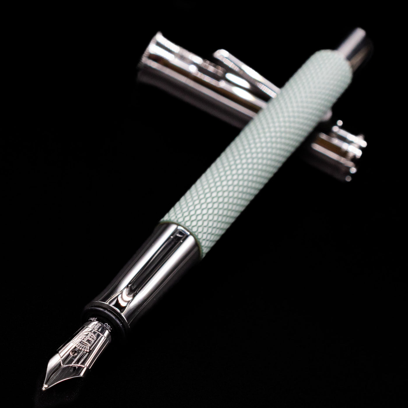 Close-up of Graf von Faber-Castell Guilloche Sage Green Fountain Pen nib with cap in background