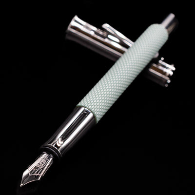Close-up of Graf von Faber-Castell Guilloche Sage Green Fountain Pen nib with cap in background