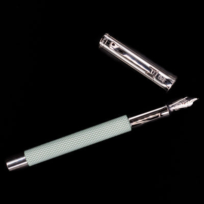 Side view of Graf von Faber-Castell Guilloche Sage Green Fountain Pen with cap laid beside