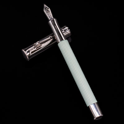 Open Graf von Faber-Castell Guilloche Sage Green Fountain Pen with cap beside it on black background