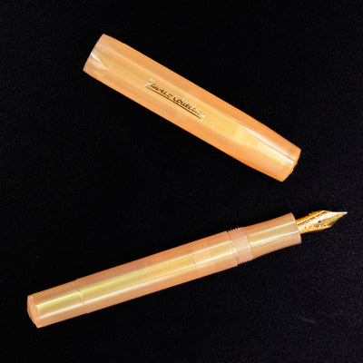 Flatlay image of the Kaweco Apricot Pearl fountain pen and cap, highlighting pearlescent barrel and compact design.