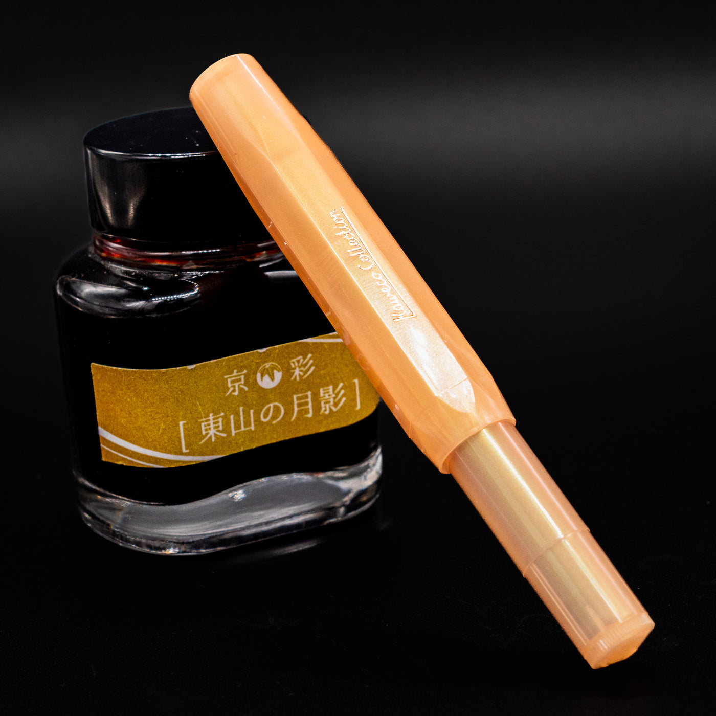 Kaweco Collector's Sport Apricot Pearl Fountain Pen shown capped, resting against a Japanese ink bottle.