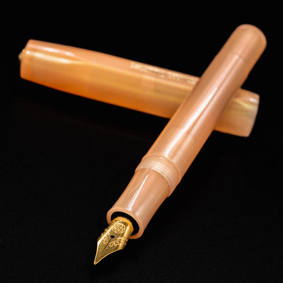 Angled close-up of the Kaweco Collector's Sport Apricot Pearl fountain pen, highlighting the shimmer and gold nib.