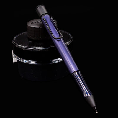 LAMY Al Star Mechanical Pencil in Dark Dusk resting diagonally on a black LAMY ink bottle against a black background