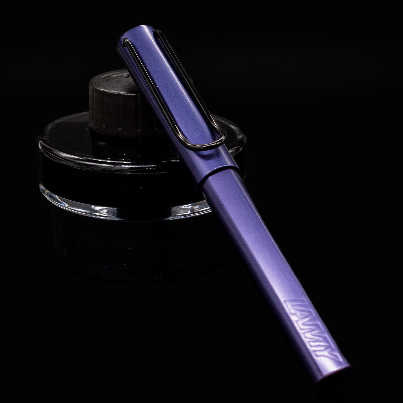 Capped LAMY Al-Star Dark Dusk Rollerball Pen resting on black LAMY ink bottle