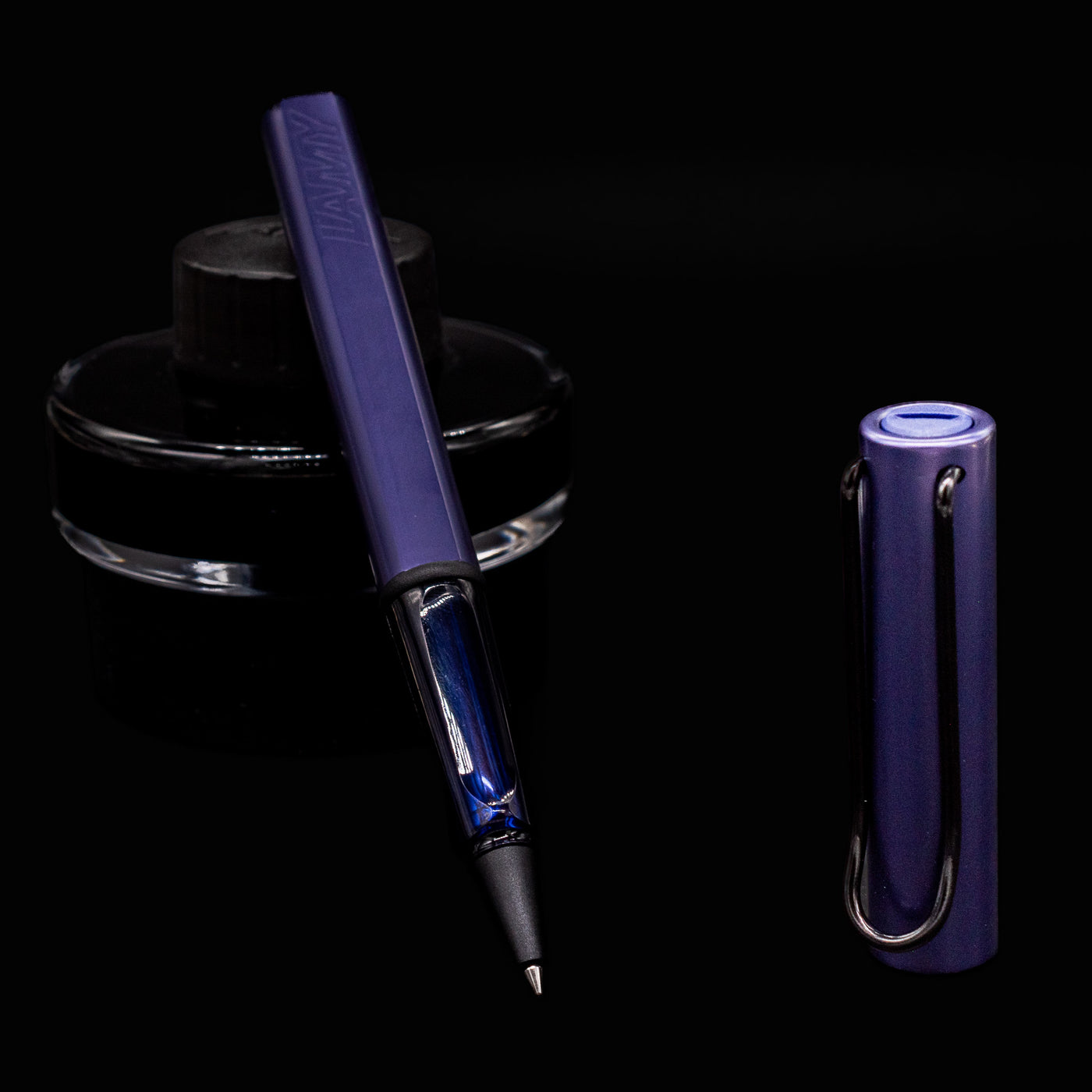 LAMY Al-Star Rollerball Pen in Dark Dusk uncapped with ink bottle background, showing transparent grip section