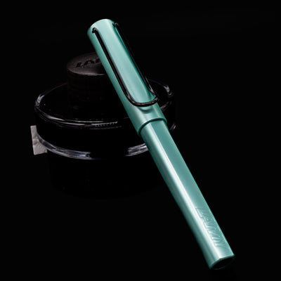 LAMY Al Star Rollerball Pen in Mint shown capped and resting against a LAMY ink bottle