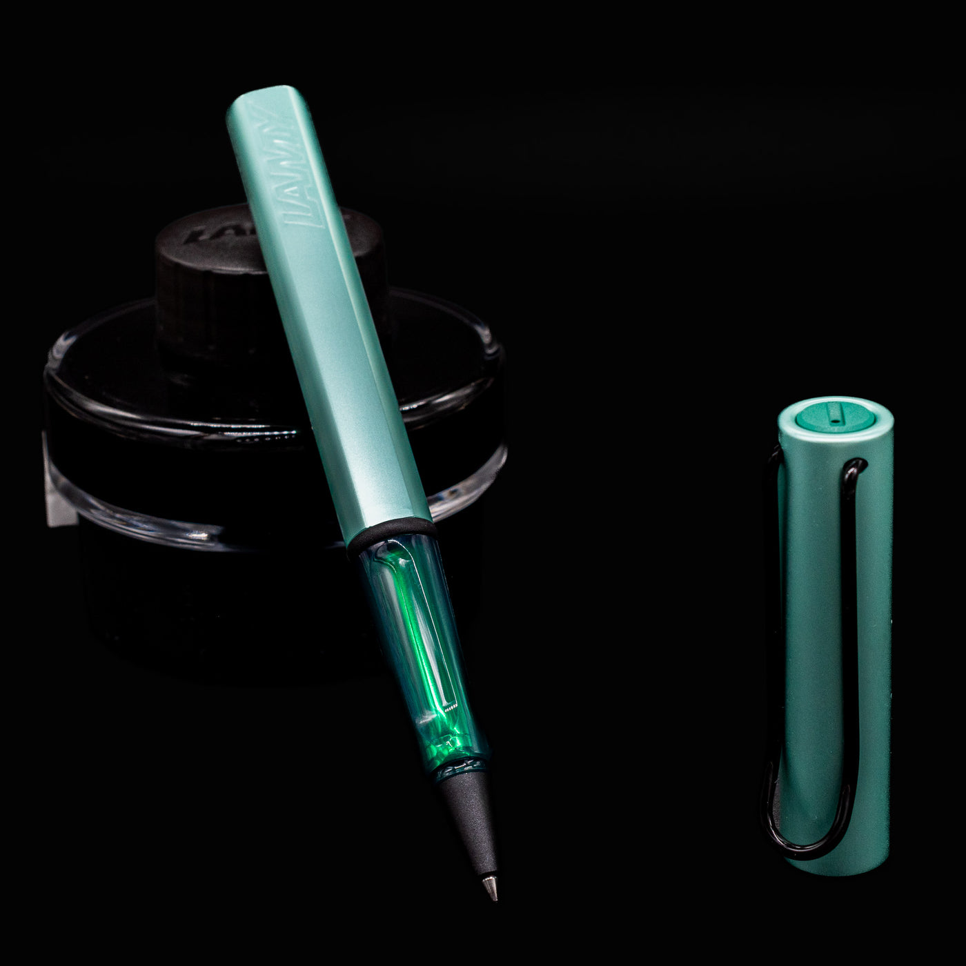 Close-up of uncapped LAMY Al Star Rollerball Pen in Mint color with black ink bottle background