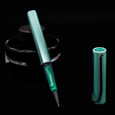 Close-up of uncapped LAMY Al Star Rollerball Pen in Mint color with black ink bottle background