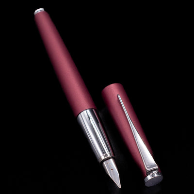 Maroon pen with silver accents on a black background