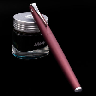 LAMY studio rollerball pen orion capped, leaning on an ink bottle.