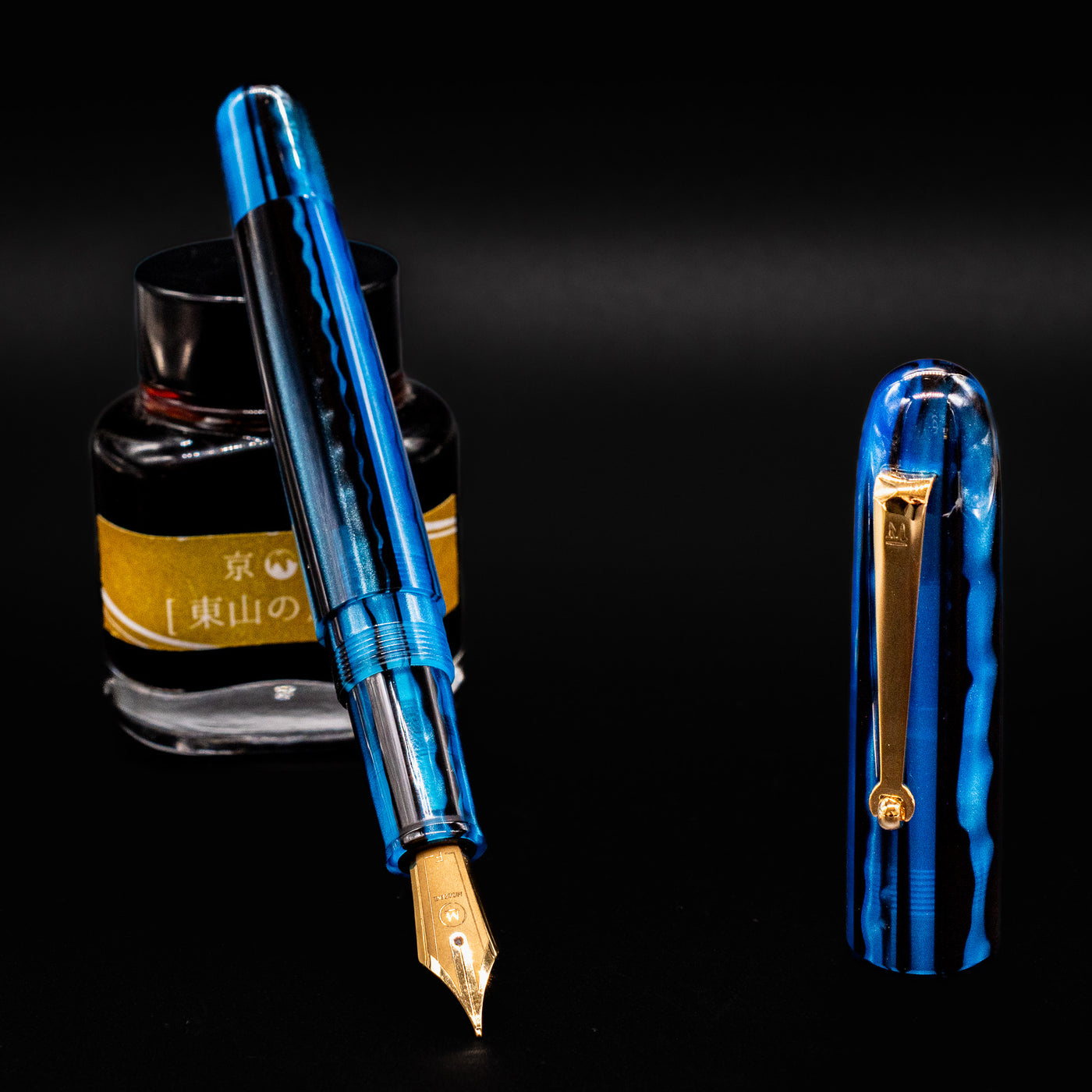 Molteni Modelo 71 Blue & Gold Fountain Pen with nib exposed and cap upright beside an ink bottle.
