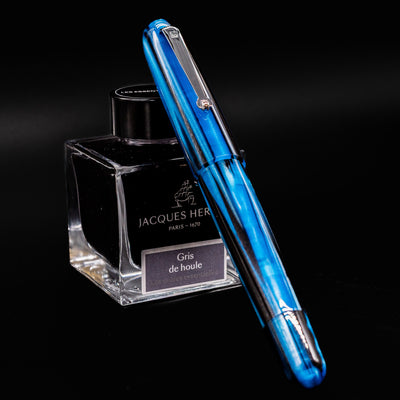 Molteni Modelo 71 Blue & Rhodium Fountain Pen displayed upright in front of Jacques Herbin Gris de Houle ink bottle.