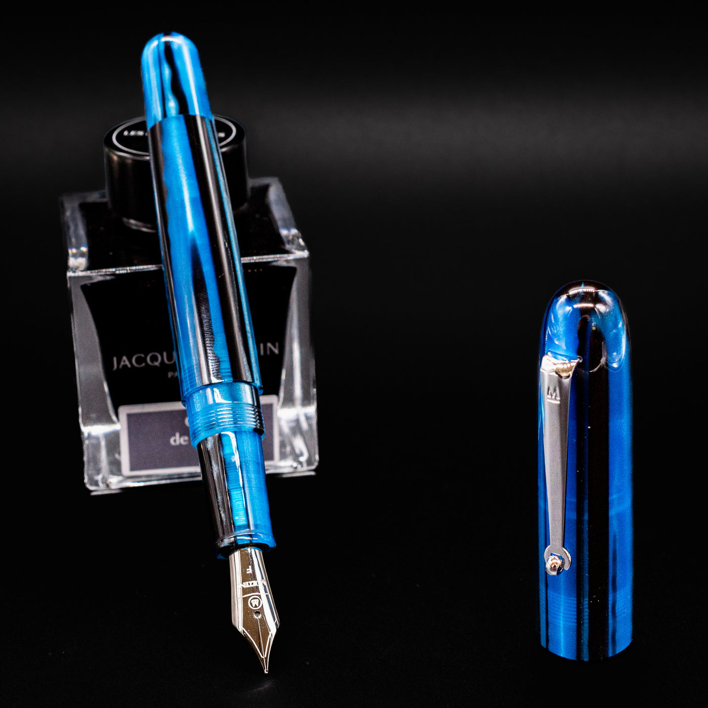 Uncapped Molteni Modelo 71 Blue & Rhodium Fountain Pen with ink bottle in the background.