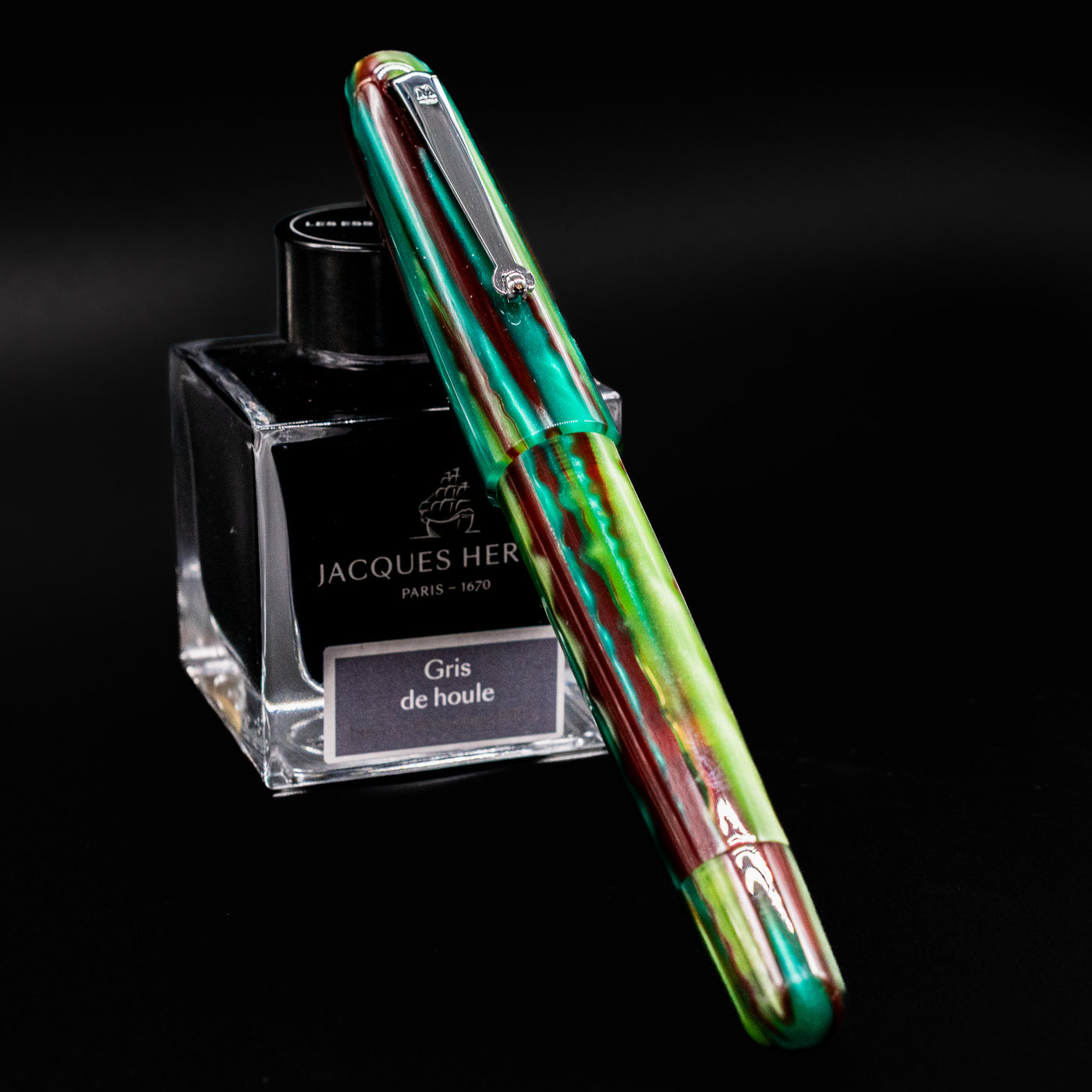 Molteni Modelo 71 Fountain Pen in Green and Rhodium finish, shown capped in front of Jacques Herbin Gris de Houle ink bottle