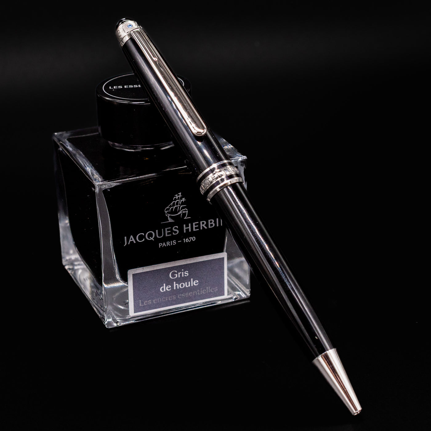 Montblanc Meisterstück 164 UNICEF Black & Platinum Ballpoint Pen resting on Jacques Herbin ink bottle – preowned luxury writing instrument