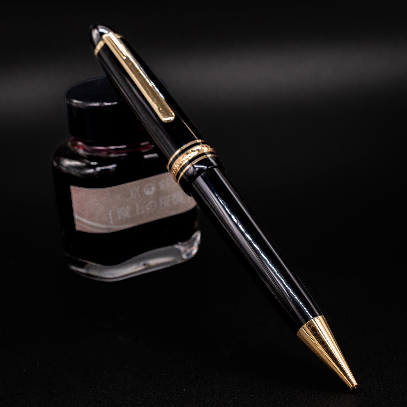 Preowned Montblanc Meisterstück 167 LeGrand Mechanical Pencil in black and gold displayed beside an ink bottle for contrast.