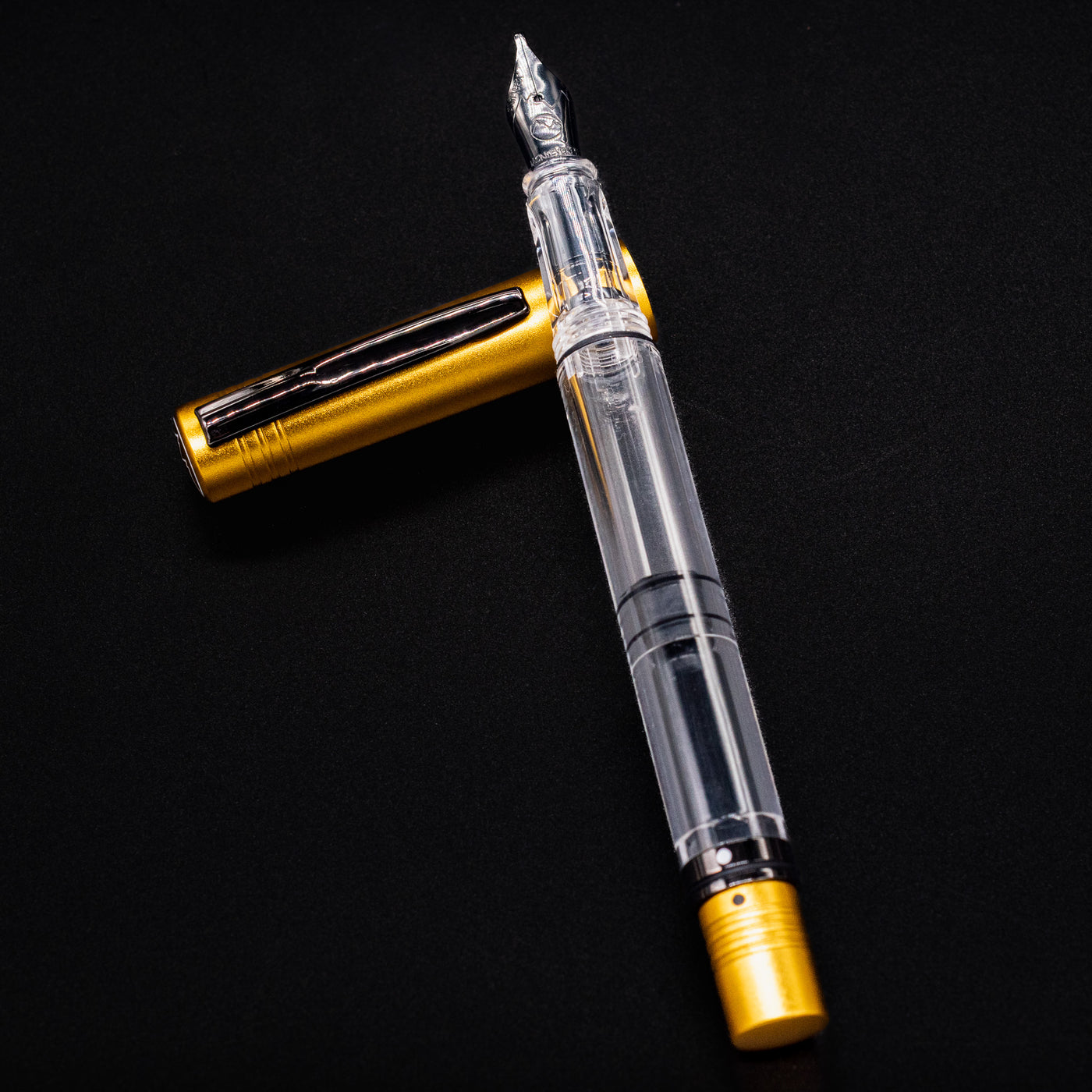 Flat lay image of the Monteverde MP1 Honey Yellow Fountain Pen with cap off, showcasing its clear piston-fill barrel.