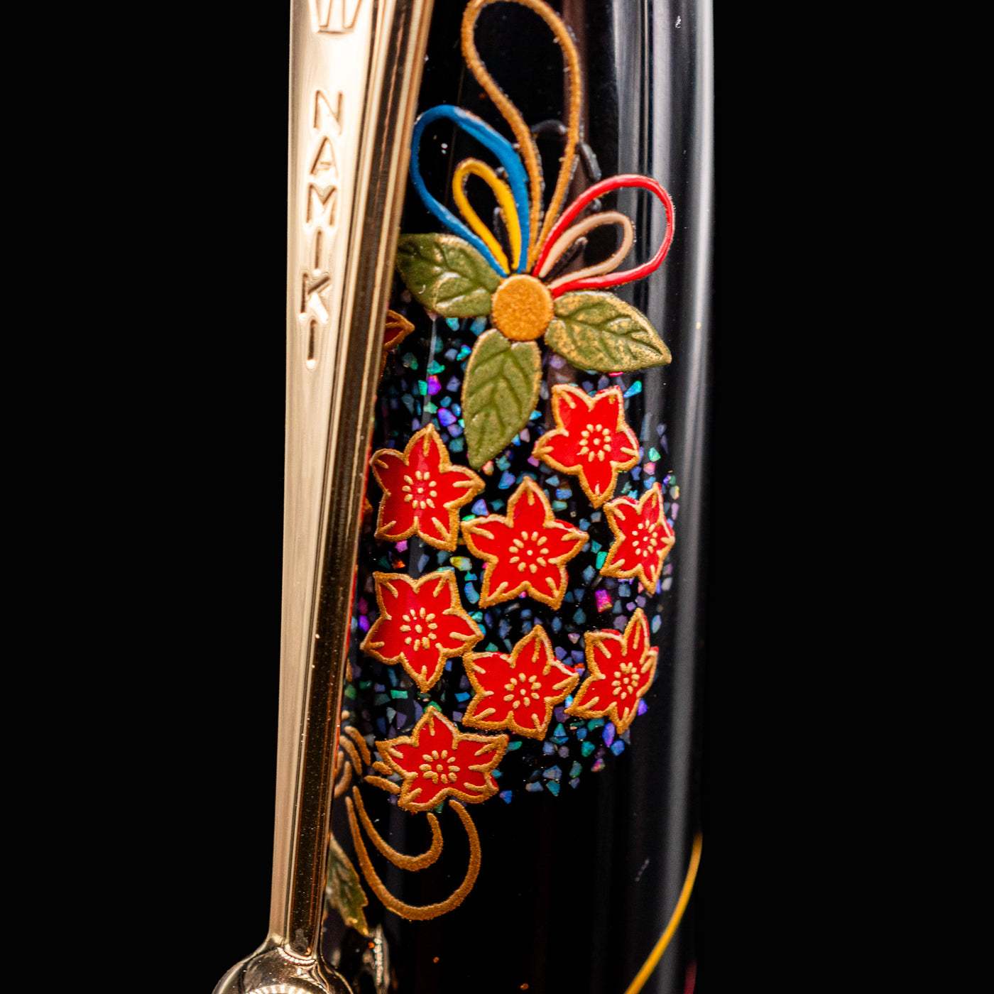 Close-up of Namiki Yukari Maki-e Fountain Pen cap with red floral maki-e and engraved gold clip