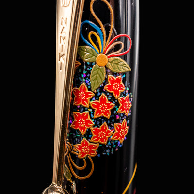 Close-up of Namiki Yukari Maki-e Fountain Pen cap with red floral maki-e and engraved gold clip