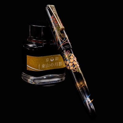 Namiki Yukari Maki-e Fountain Pen - Herb Decoration shown capped beside Kyonooto ink bottle