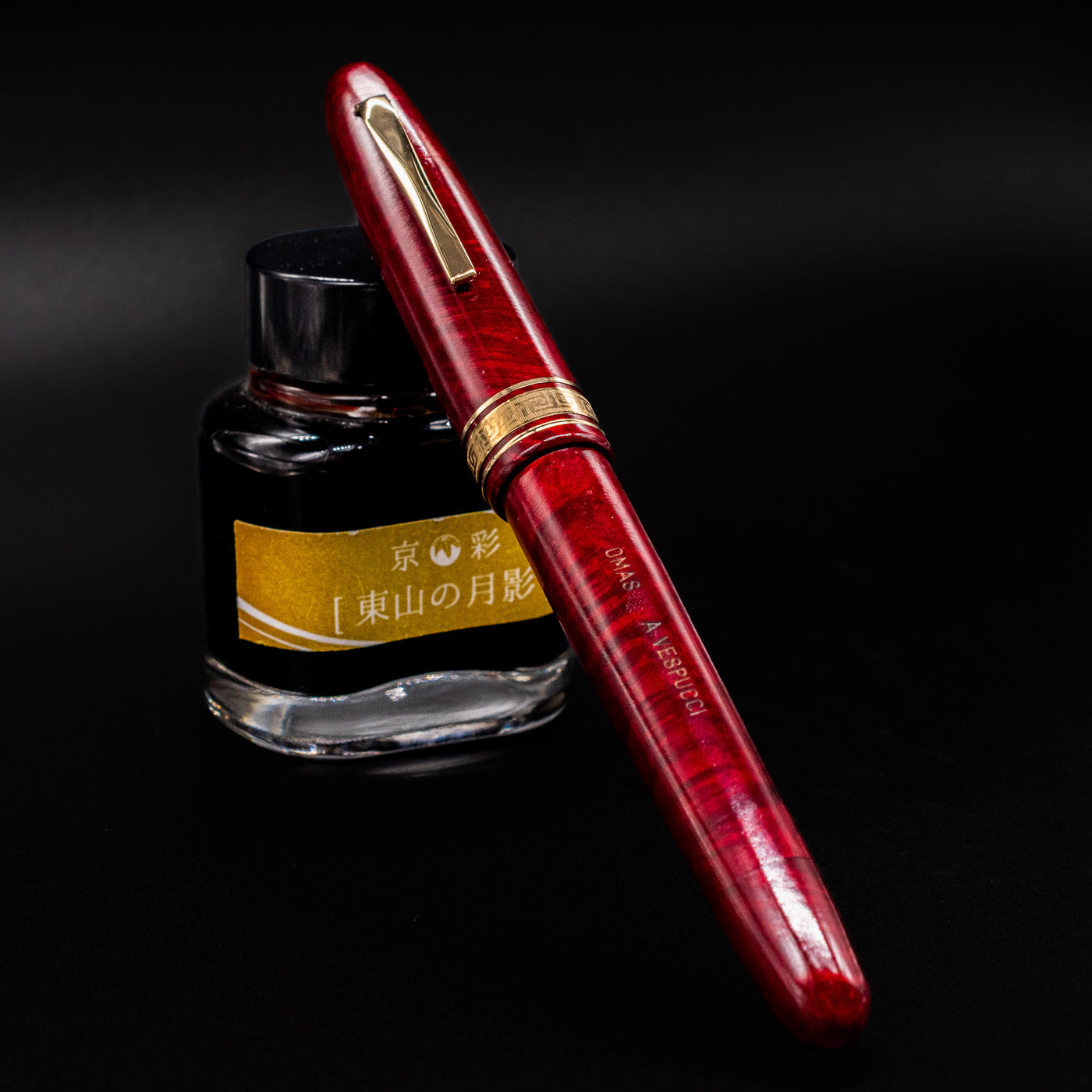 OMAS AM87 Briarwood fountain pen capped, resting on an ink bottle