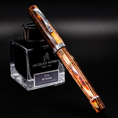 Omas Grand Paragon Brown Arco ST Fountain Pen leaning against Jacques Herbin Gris de Houle ink bottle