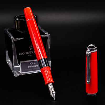 Uncapped Pelikan Classic M205 Fountain Pen - Red, standing beside Jacques Herbin Gris de Houle ink