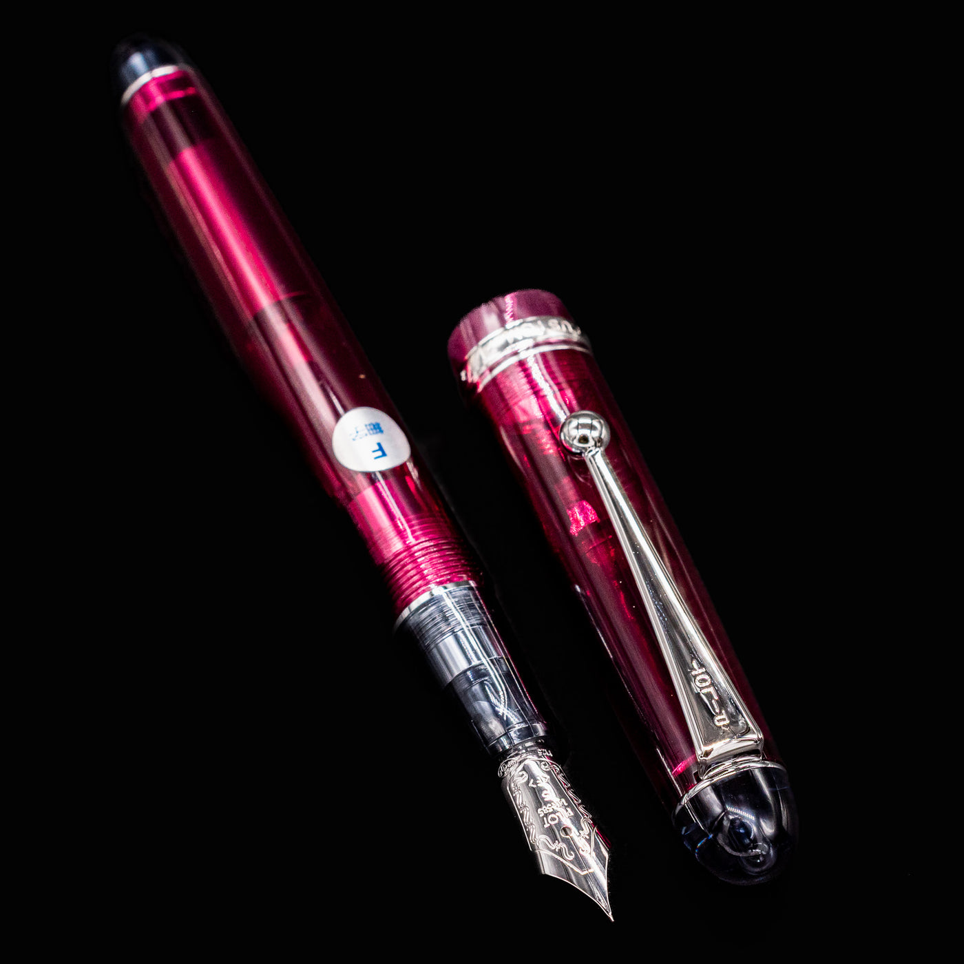 Disassembled Pilot Custom 74 Merlot fountain pen showing nib and cap side by side on black background