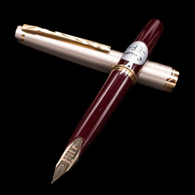 Pilot E95S Fountain Pen Burgundy and Ivory with cap and barrel displayed in a cross layout