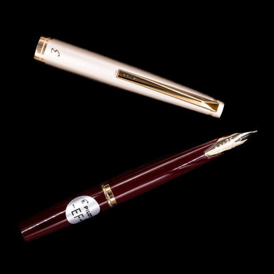 Flat lay of uncapped Pilot E95S Fountain Pen Burgundy and Ivory with nib and cap shown separately